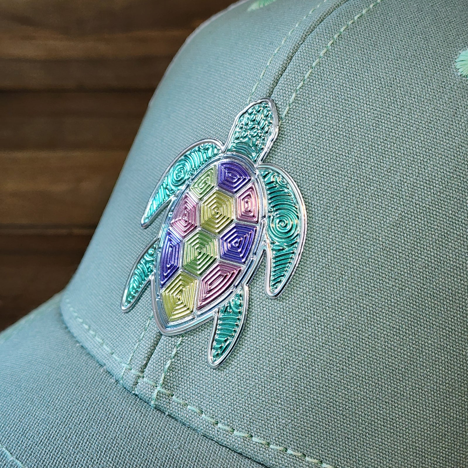 Detailed view of textured metallic loggerhead turtle patch on women’s pastel ponytail trucker hat