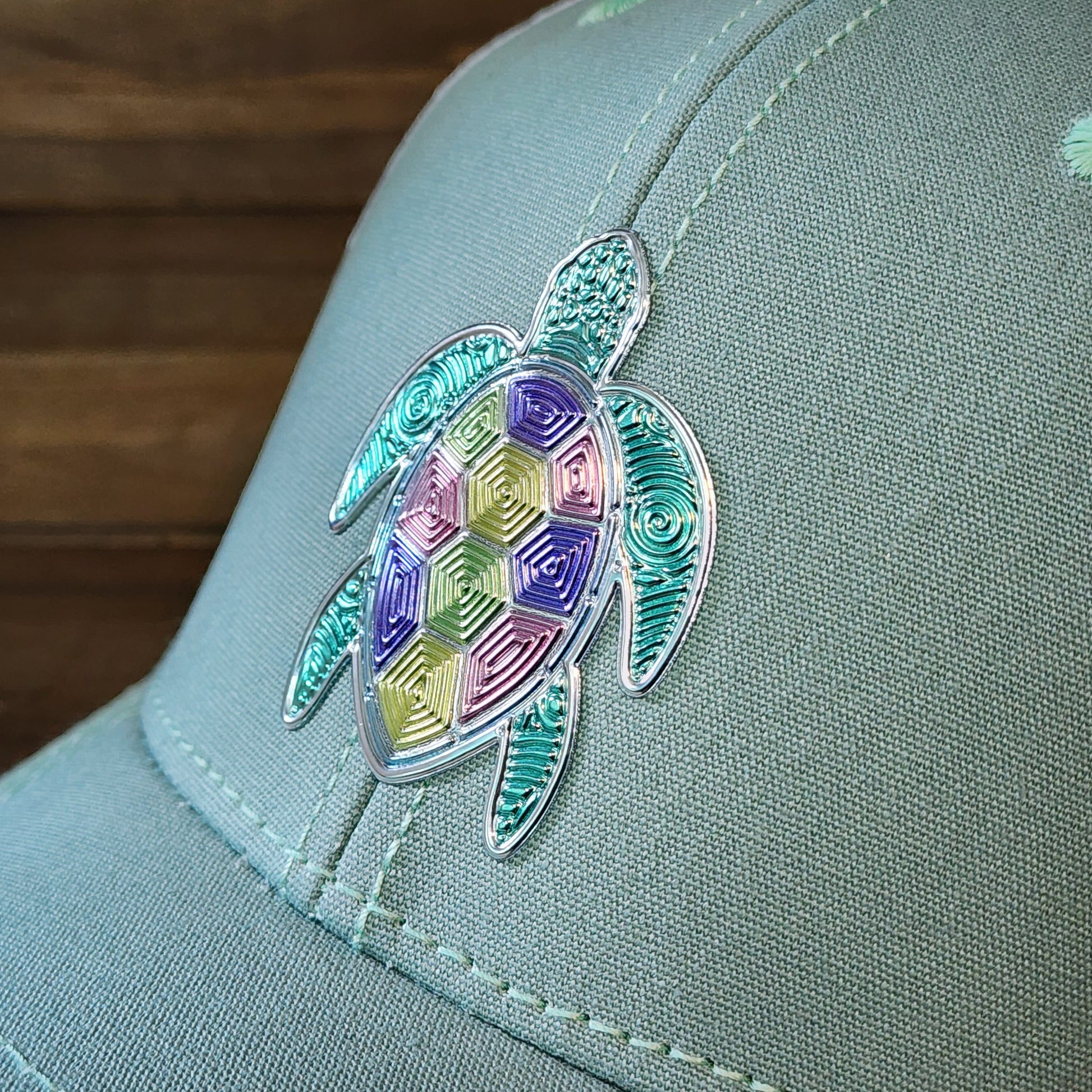 Detailed view of textured metallic loggerhead turtle patch on women’s pastel ponytail trucker hat